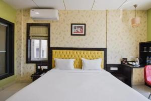 1 dormitorio con 1 cama blanca grande y cabecero amarillo en Goroomgo Royal Crown Puri, en Puri
