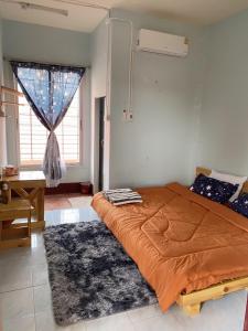 a bedroom with a bed with an orange comforter and a window at CTM.INN (SISAKET)THAILAND 