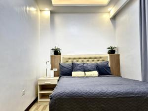ein Schlafzimmer mit einem Bett mit blauer Bettwäsche und zwei Pflanzen in der Unterkunft Casa Dee Leticia in Sibalom