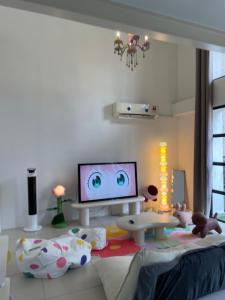 - un salon avec une télévision et un lit, ainsi qu'une chambre dotée d'ours dans l'établissement Cozy Party House in Damansara Perdana - Perfect Location, à Petaling Jaya