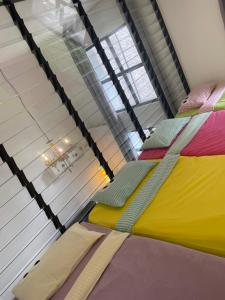 - une chambre avec 2 lits et des draps colorés dans l'établissement Cozy Party House in Damansara Perdana - Perfect Location, à Petaling Jaya
