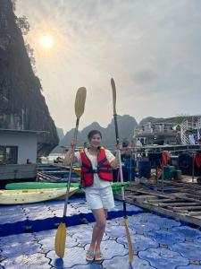 Eine Frau steht mit zwei Paddeln auf einem Boot in der Unterkunft People's House Sea View O Giang in Noi Bai