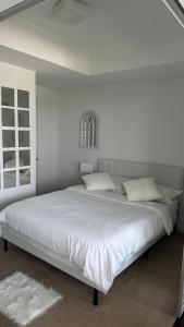 een witte slaapkamer met een groot bed met witte lakens bij DOWNTOWN, LUXURY CONDO, CN TOWER, ROGERS CENTER, SCOCIA ARENA, UNOBSTRUCTED VIEW in Toronto