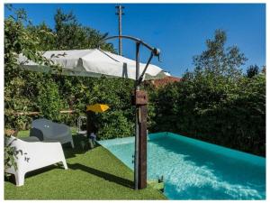 una piscina con sombrilla junto a una silla blanca en Villa Rignano Comfortable holiday residence, en Rignano sullʼArno