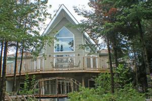a house with a deck with a balcony at Tip-of-Peninsula Lookout Cottage in Tobermory