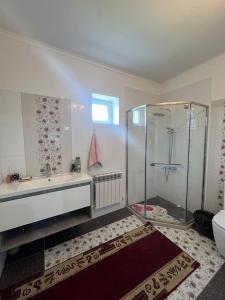 a bathroom with a shower and a tub and a sink at Korkem in Shymkent