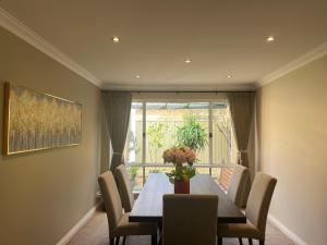 珀斯Applecross 2 Bedrooms by Swan River的一间有桌子、椅子和窗户的餐厅