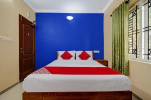 - une chambre bleue avec un grand lit et des oreillers rouges dans l'établissement OYO Kakkanad Heights Inn, à Kakkanad