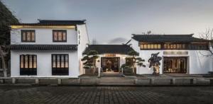Biały budynek z pomnikiem przed nim w obiekcie Yihe Riverside Suzhou w mieście Suzhou