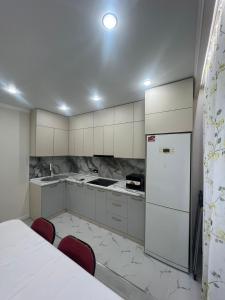 een keuken met witte kasten, een koelkast en rode stoelen bij Однокомнатная квартира на ЖК Sensata City in Shugyla