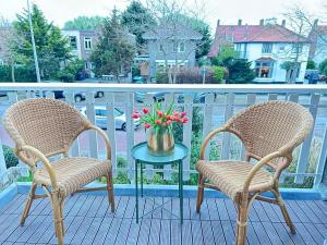 2 stoelen en een tafel met bloemen op een balkon bij Lovely Spacious Apartment in Zandvoort