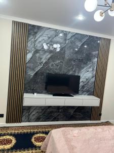 een kamer met een tv aan een muur met een marmeren muur bij Однокомнатная квартира на ЖК Sensata City in Shugyla