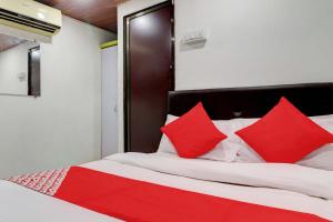 a red and white bed with red pillows on it at Hotel Memsaab Family Residency in Mumbai