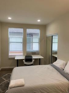 a bedroom with a bed and a desk and two windows at San Jose Shark House - Unit 1 in San Jose