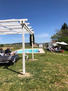 eine Gruppe von Menschen, die unter einer Pergola neben einem Pool sitzen in der Unterkunft B&B Prato San Lorenzo in Nocciano