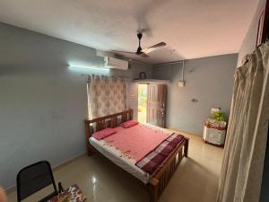 a bedroom with a bed in a room with a fan at KENSON HOMESTAY in Mangalore