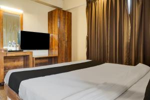 a bedroom with a bed and a flat screen tv at Collection O Hotel Nanashree Grand in Pune
