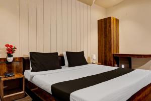 a bedroom with a large bed with black pillows at Collection O Hotel Nanashree Grand in Pune