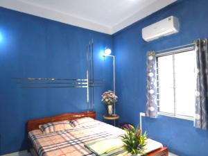 a blue bedroom with a bed and a window at alley homestay in Hanoi