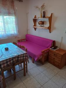 sala de estar con sofá púrpura y mesa en Anestis Apartments & rooms, en Palaión Tsiflíkion