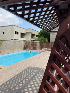 a patio with a swimming pool and a wooden deck at Stay Play Away Residences - Luxury 4 bed, Airport Residential, Accra in Accra
