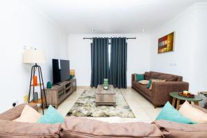 sala de estar con 2 sofás y TV en Stay Play Away Residences - Luxury 4 bed, Airport Residential, Accra en Accra