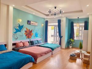 2 camas en una habitación con paredes azules en PINETOWN Homestay, en Da Lat