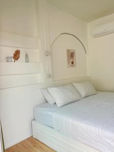 a white bedroom with a bed with white sheets at Baancaptainhook pool kohlarn in Ko Larn
