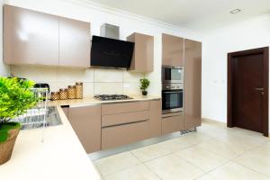 a kitchen with stainless steel appliances and brown cabinets at Stay Play Away Residences - Luxury 5 bed, Airport Residential in Accra