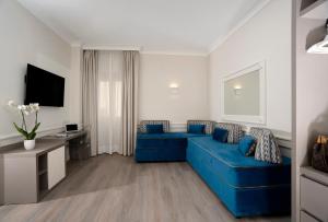 Hotel Michelangelo في سورينتو: غرفة معيشة مع أريكة زرقاء ومكتب