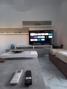 uma sala de estar com dois comandos remotos e uma televisão em Νεόκτιστη βίλα, Χώρα Πυθαγορείου em Pythagoreio