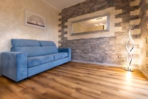 a blue couch in a living room with a brick wall at Verdemare in Duino
