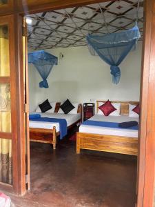 two beds in a room with blue drapes at Himansa Homestay in Ella