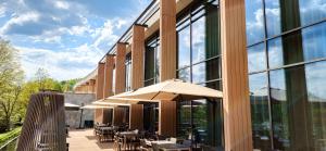 un patio al aire libre con mesas y sombrillas frente a un edificio en Hotel GLAR Conference & SPA en Wisełka
