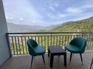 twee stoelen en een tafel op een balkon met bergen bij Kamlesh Lodge in Bhavnagar