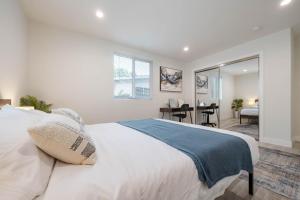 a bedroom with a large white bed and a desk at Modern NOHO Gem! in Los Angeles