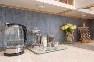 a kitchen counter with a coffee pot and cups and flowers at Modern NOHO Gem! in Los Angeles