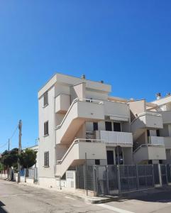 een wit appartementencomplex met een hek ervoor bij La Vela Apartaments - Porto Cesareo in Porto Cesareo