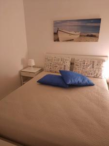 een slaapkamer met een bed met een blauw kussen erop bij La Vela Apartaments - Porto Cesareo in Porto Cesareo