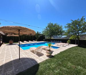 a swimming pool with chairs and an umbrella and a yard at Alojamiento turístico Loma Alta in Cambil