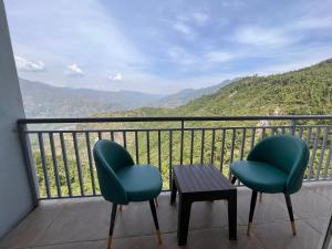 2 Stühle und ein Tisch auf einem Balkon mit Bergblick in der Unterkunft Shekhar Royal classic in Bhavnagar