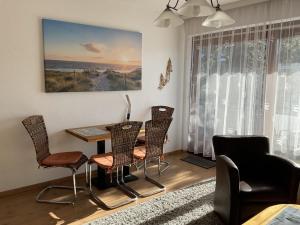 ein Wohnzimmer mit einem Tisch, Stühlen und einem Gemälde in der Unterkunft Muschelbank in Büsum