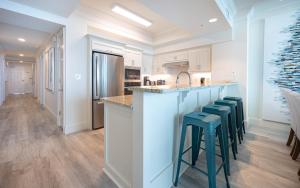 a kitchen with white cabinets and blue stools at a counter at Perdido Dunes Tower 9E condo in Orange Beach