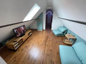 Ático con sala de estar con sofá y TV en La Parenthèse Bucolique, en Aire-sur-la-Lys