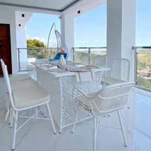 een witte tafel en stoelen in een kamer met een balkon bij Jacobs Makiling Lakeview Resort in Los Baños