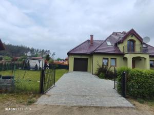 a yellow house with a gate and a driveway at Zielony Dom in Wolin