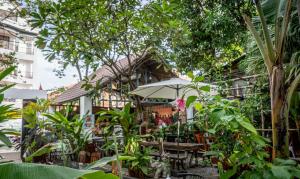 um restaurante com guarda-sol, cadeiras e árvores em Maison 557 em Siem Reap