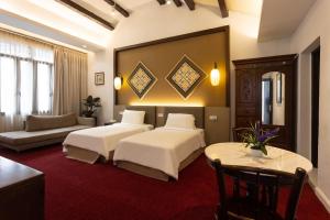 Habitación de hotel con 2 camas y sofá en Hotel Puri Melaka en Melaka
