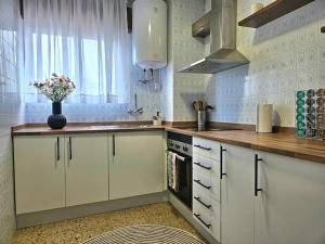 a kitchen with white cabinets and a vase of flowers at Un balcón sobre el mar in Villanueva de Arosa