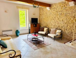 sala de estar con sillas, mesa y pared de piedra en Loca-Moulins, en Saze